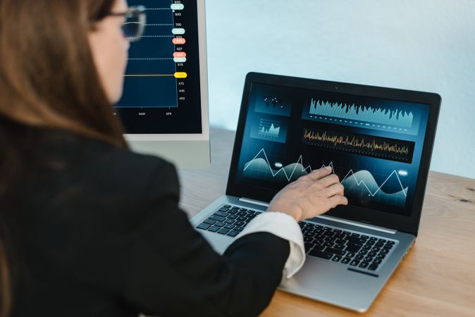 Woman pointing at laptop with financial charts