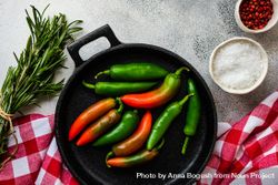 Iron cast pan with rosemary bunch and spicy peppers with seasoning 0v3ynx
