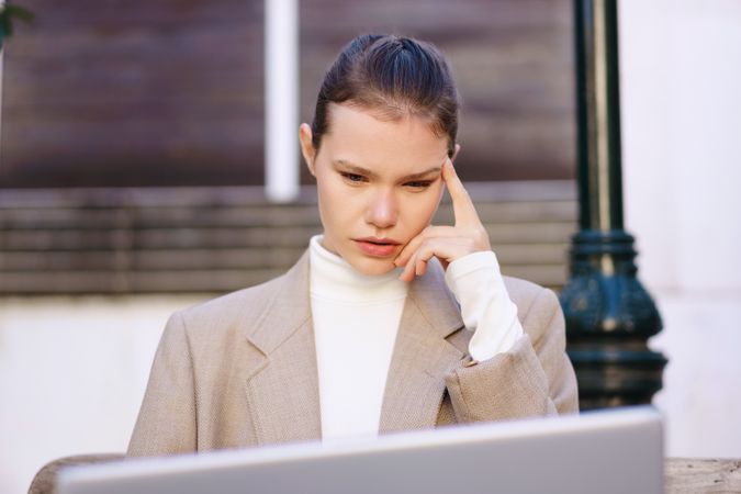 A businesswoman analyzes data on her laptop in a bustling city, showcasing her professionalism