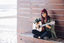 Romantic woman playing guitar leaning on wall