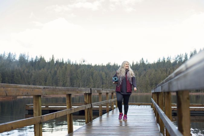 Woman walking on a lake dock with trees in background