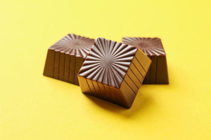 Tasty chocolate candies on yellow background, close up