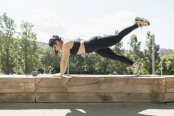 A young woman performs arms and leg exercises to strengthen buttocks and biceps, gaining balance and strength