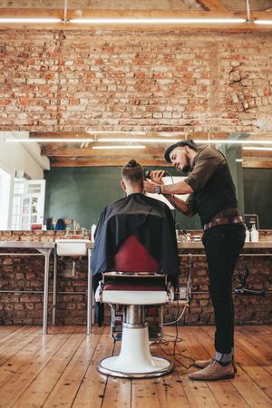 Hairstylist using hair clipper in barbershop