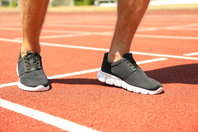 Man in sneakers on red athletic running track, close up