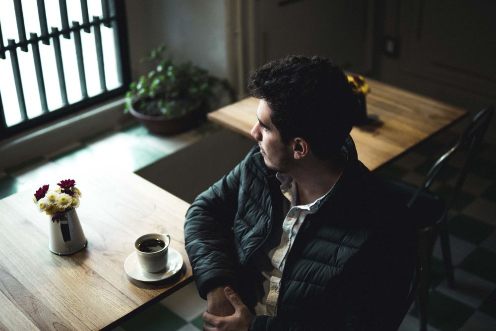 Man sitting at wooden table with a cup of coffee on it