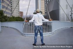 Male in denim standing with open arms on bridge above city 41Zz8b