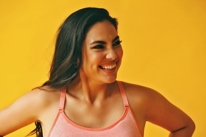 Headshot of smiling Hispanic woman with hands on her hips in yellow room