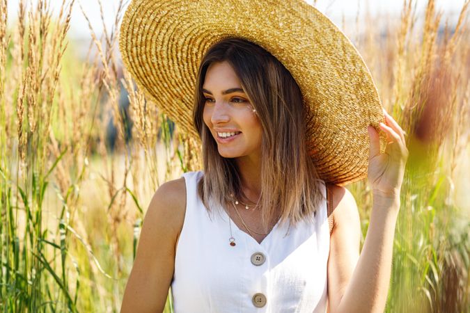 Portrait of happy female in a field outside in sundress and sunhat