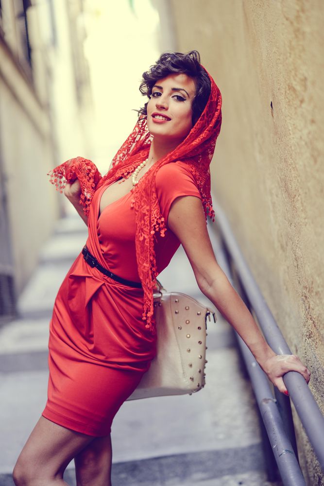 Elegant woman in dress leaning on rails of outdoor staircase