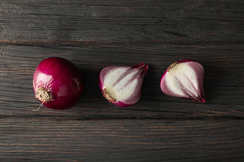 Flat lay composition with red onion on wooden background