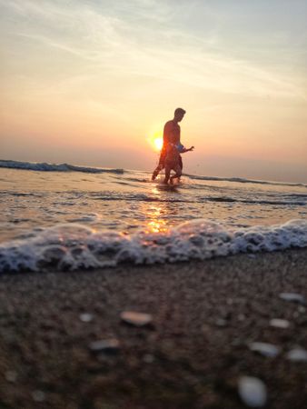 A father and daughter swim on the beach at dusk