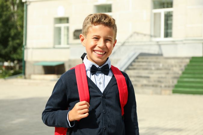 Boy with backpack against school building, space for text