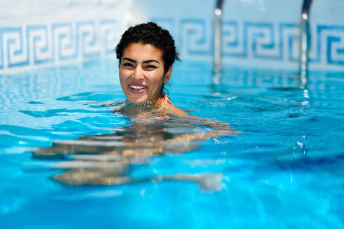 Beautiful Arab woman smiling floating in swimming pool
