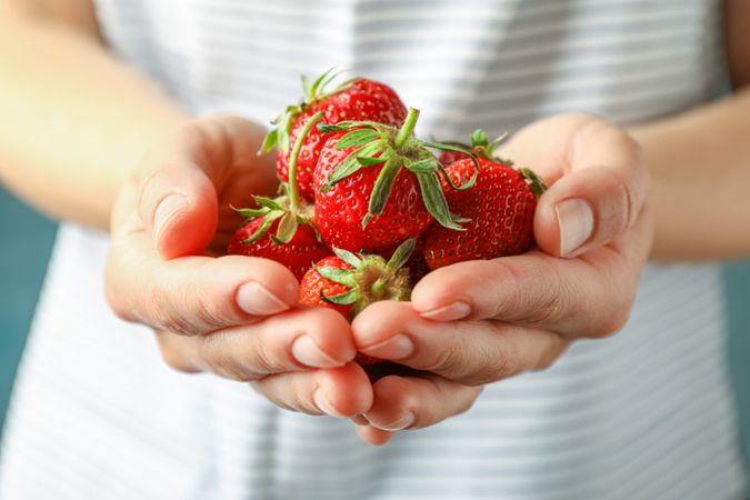 Young woman holding fresh strawberries, space for text and closeup. Summer sweet fruits and berries
