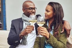 Happy Black couple looking into each others eyes with wine in hand
