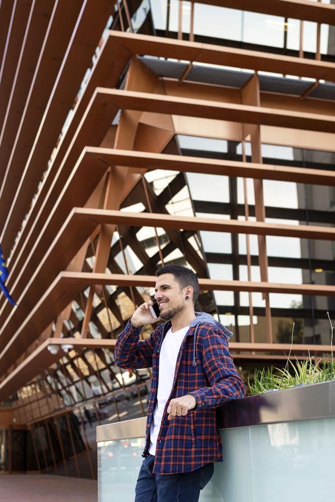 Man leaning on a wall and chatting using a smartphone