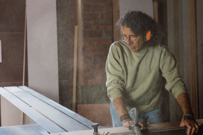 Carpenter cutting wood with circular saw in joinery