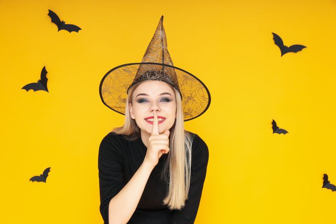 Concept of Halloween, young woman on yellow background