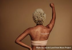 Rear view portrait of Black woman standing with arm raised on protest 56Rjd5