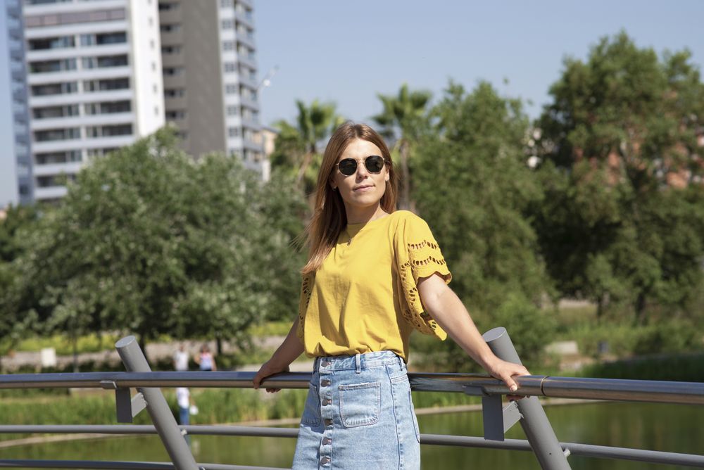 Young woman in sunglasses leaning on handrail in park