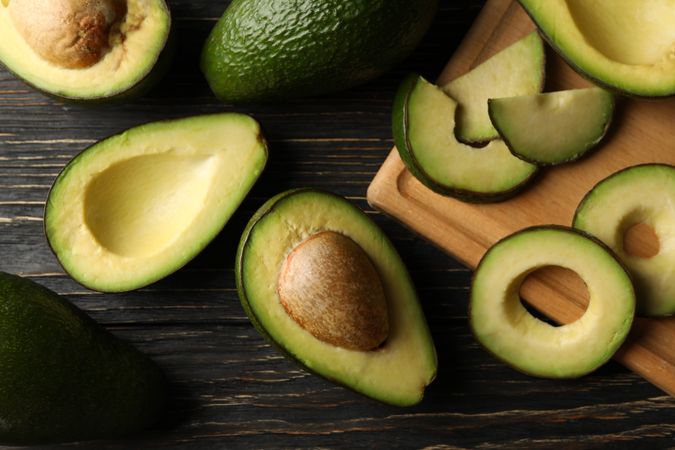 Board and avocado on wooden background, top view