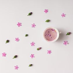 Cup of herbal tea with flowers and buds on light background