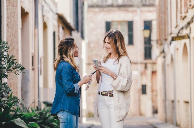 Friends walking and smiling with smartphone