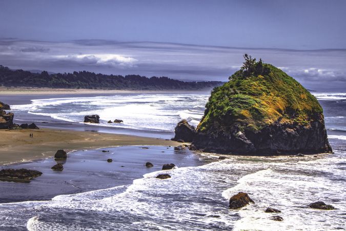 Large rock with moss on the coast with waves coming in