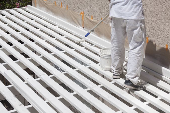 Painter Rolling Paint Onto Top of Patio Cover