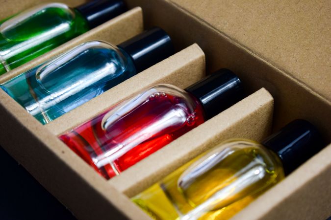 Four different colored perfume bottles in a cardboard box