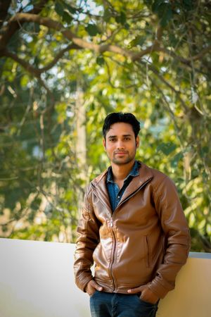 Man in brown leather jacket standing near tree