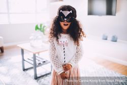 Little girl wearing a mask holding a wand B5QKVb