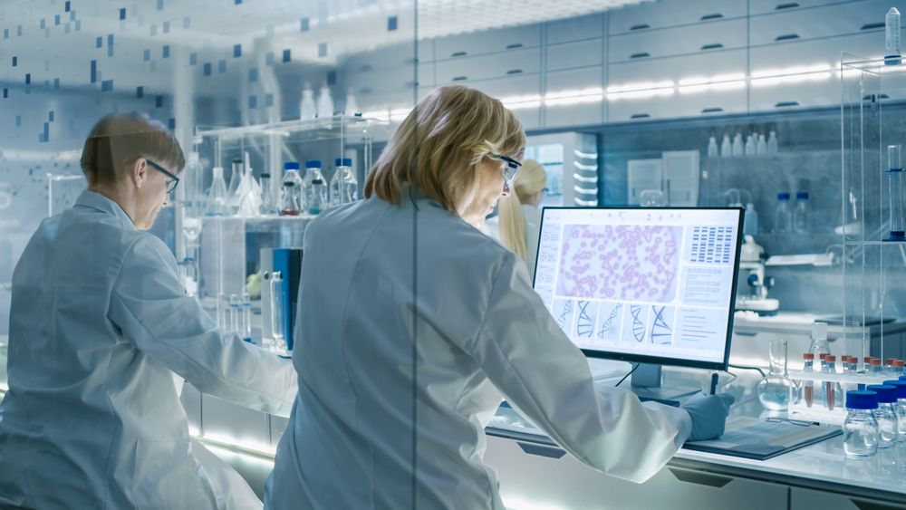 Female and Male Scientists Working on their Computers In Big Modern Laboratory.