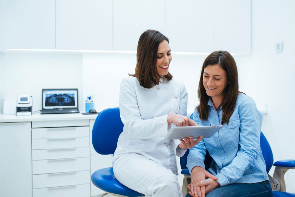 Dentist speaking with client showing document with information