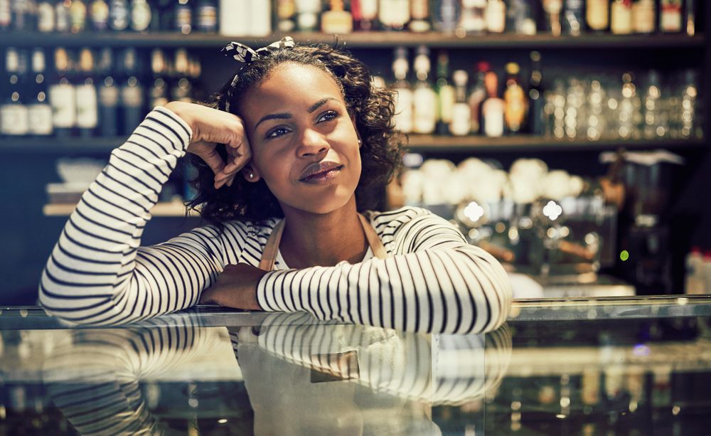Contemplative woman leaning on glass display in modern bistro