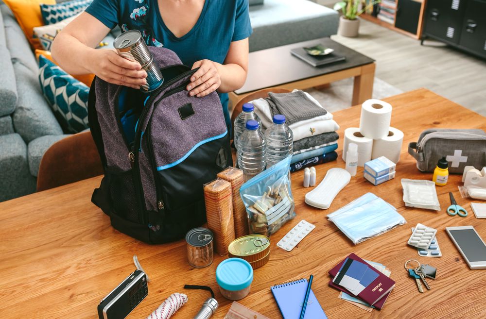 Woman putting cans of food to prepare emergency backpack
