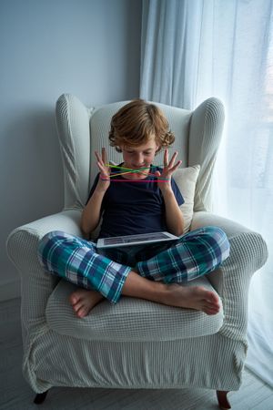 Content boy watching video while playing string game