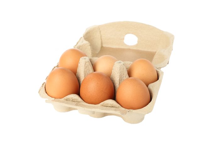 Few raw chicken eggs in carton box on blank background