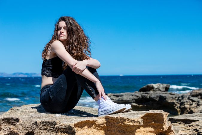 female relaxing on rocky seashore