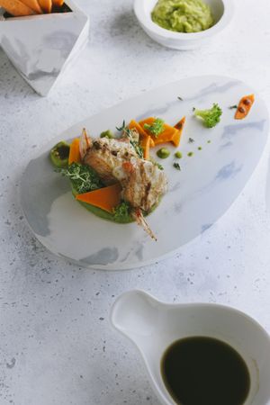 grilled scorpion fish with mashed peas and carrot sticks, on a marble plate