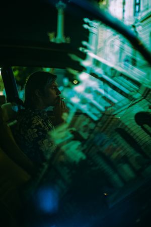 Side view of young man smoking in an old car at night