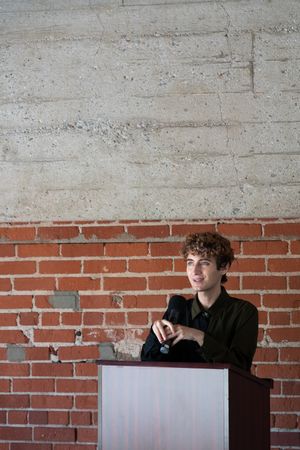 Nonbinary person at podium holding microphone