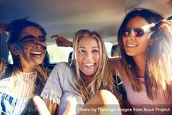 Group of female friends happy while riding in back of car 49z7Eb