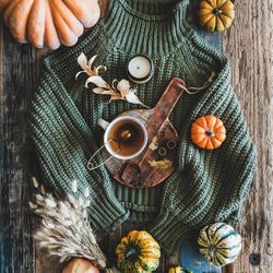 Flat-lay of dark green knitted sweater, and autumnal accessories, top view, square crop
