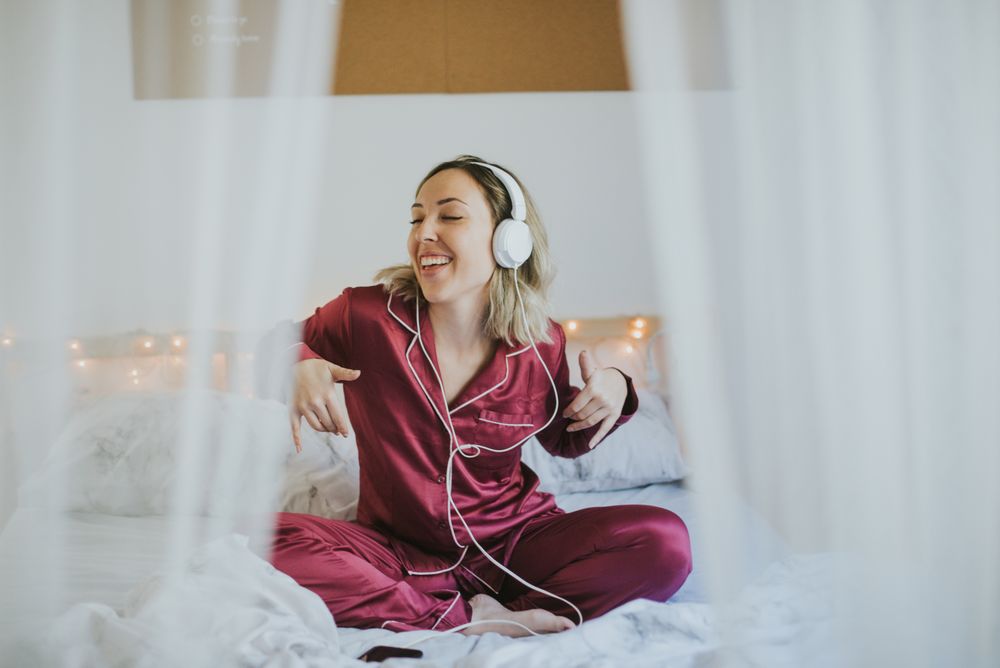 Woman with headphones listening to music in bed
