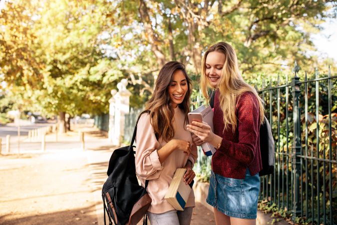 Beautiful college students looking at pictures on mobile phone