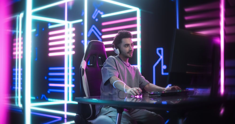 Excited Handsome Man Playing Video Games with Friends on a Computer, Surrounded by High-Tech Neon Background.