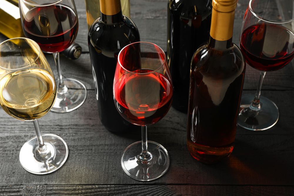Composition with bottles and glasses of different wine on wooden background