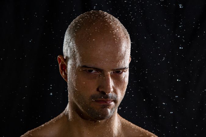 Serious bald man under rain